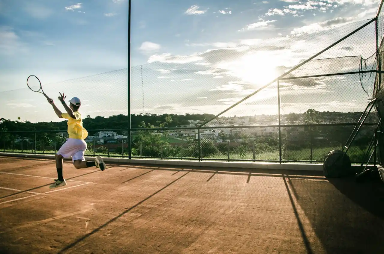 A beginner tennis player holding a racquet and ball on a clay court in Naples