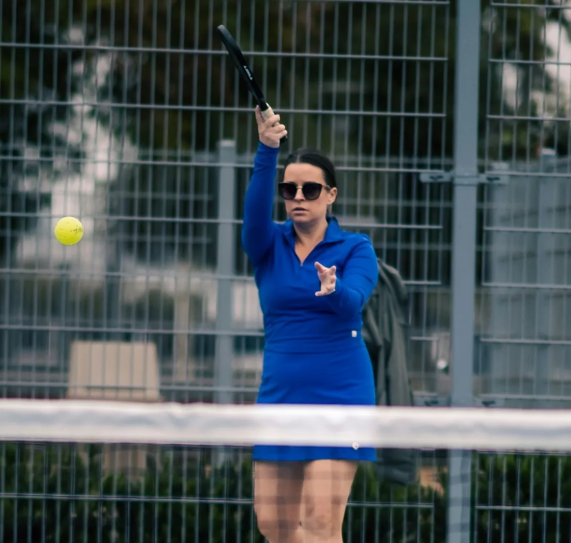 Female pickleball instructor in Dallas wearing glasses, specializing in beginner friendly private lessons.