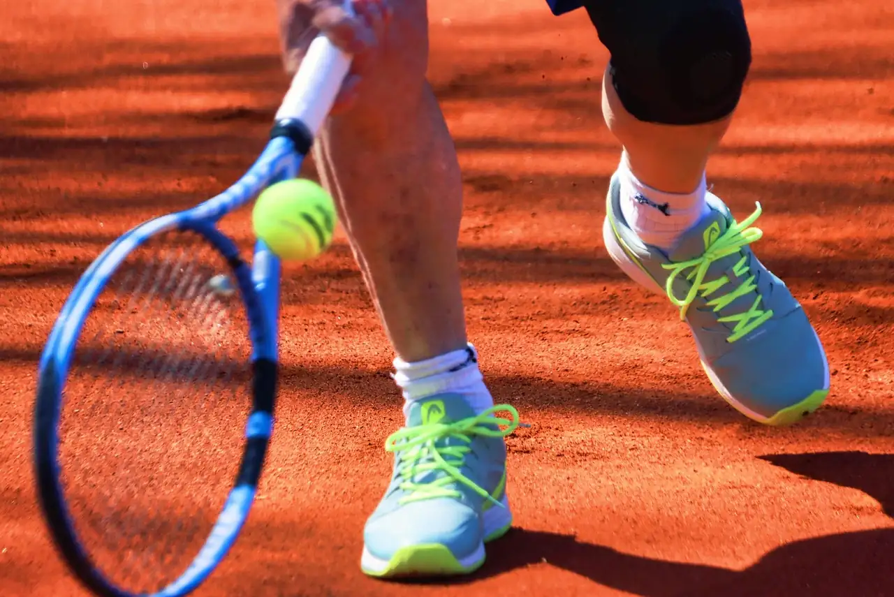 A tennis player in San Antonio reaching low for a groundstroke during an outdoor lesson