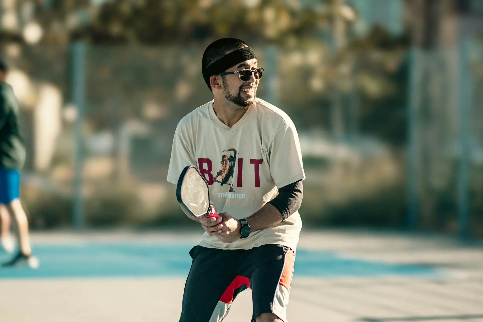 Pickleball player smiling mid-game with paddle in hand