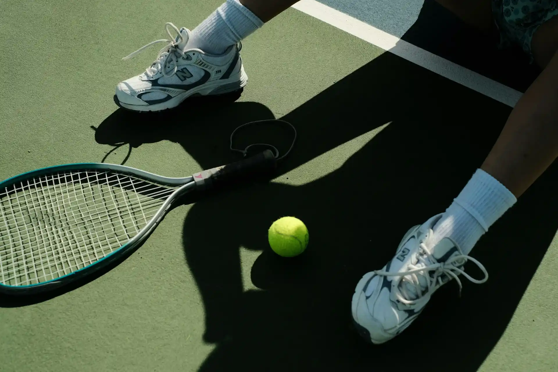 A tennis player sitting on an outdoor court with his racket resting in front of him, getting ready for a private lesson in Seattle