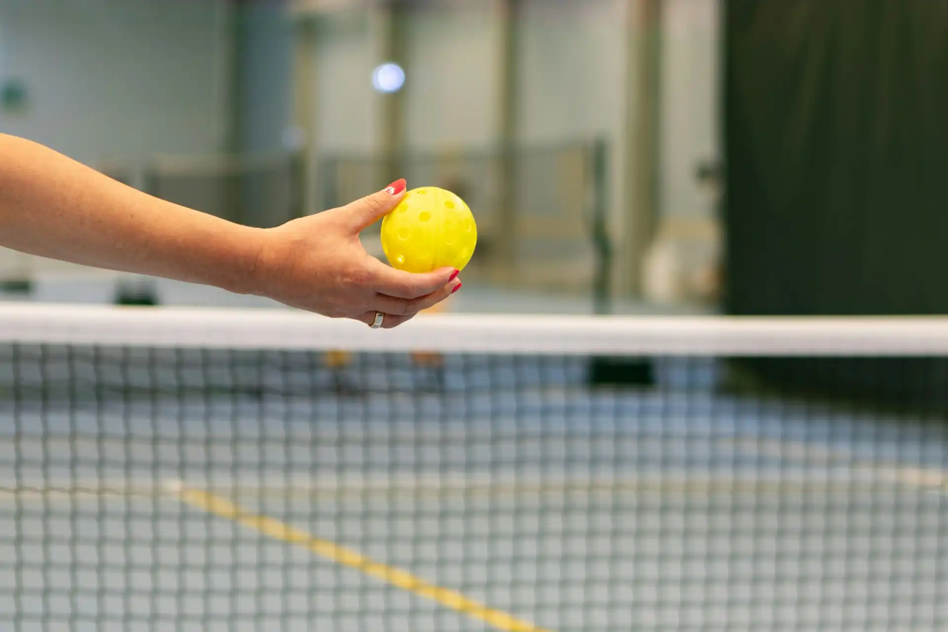 A player inspecting a pickleball inside a dedicated climate-controlled facility in Plano, TX