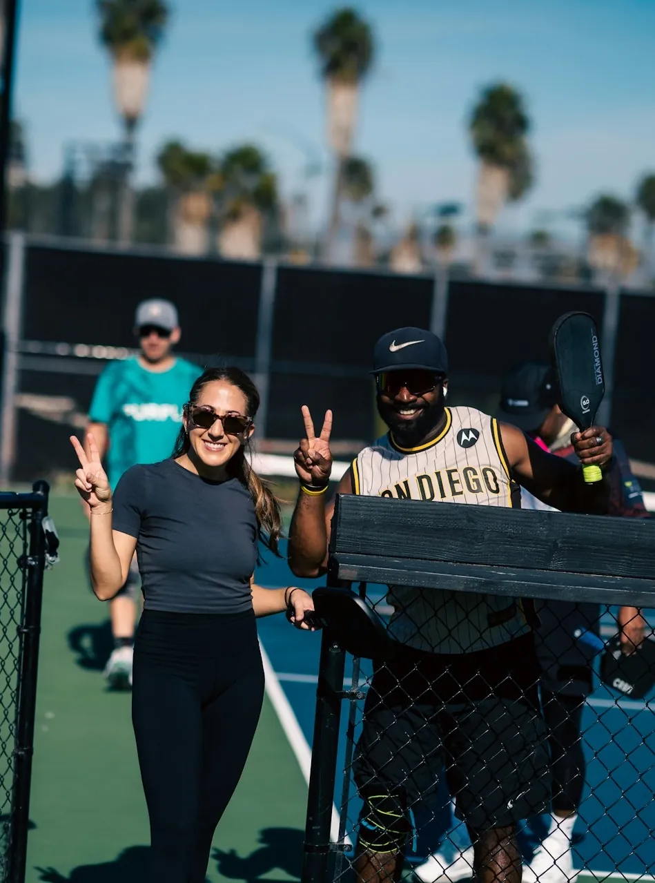 Two adults smiling in a court after they've finished private pickleball lessons