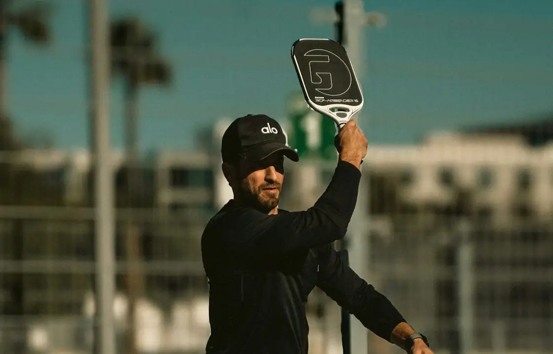 Male pickleball coach demonstrating a clean swing path while hitting a pickleball.