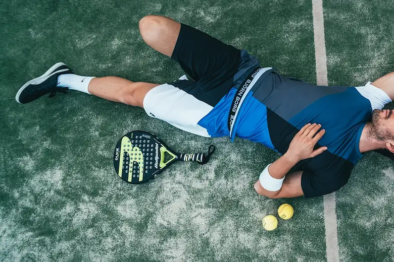 An exhausted pickleball player lying on the ground, illustrating why Patch Reef's shaded courts are necessary in the Florida heat