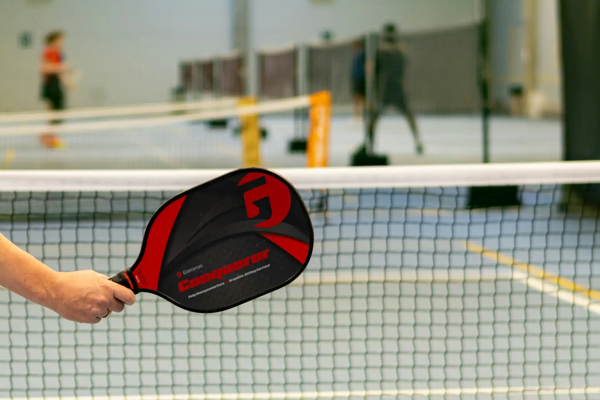 A player holding a red pickleball paddle inside a professional indoor facility in Charlotte