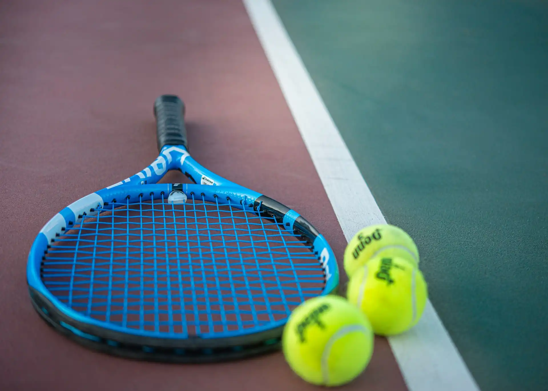 A tennis racquet and balls lying on a free public court in Plano, TX
